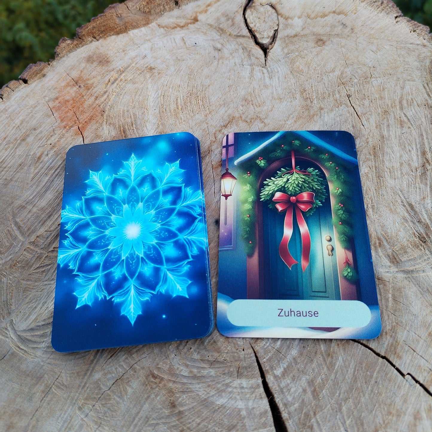Karte "Zuhause" aus dem Jahreszeiten-Kartendeck, winterliches Motiv mit Tür und Mistelzweigen, daneben blaue Kartenrückseite mit Schneflocken-Mandala