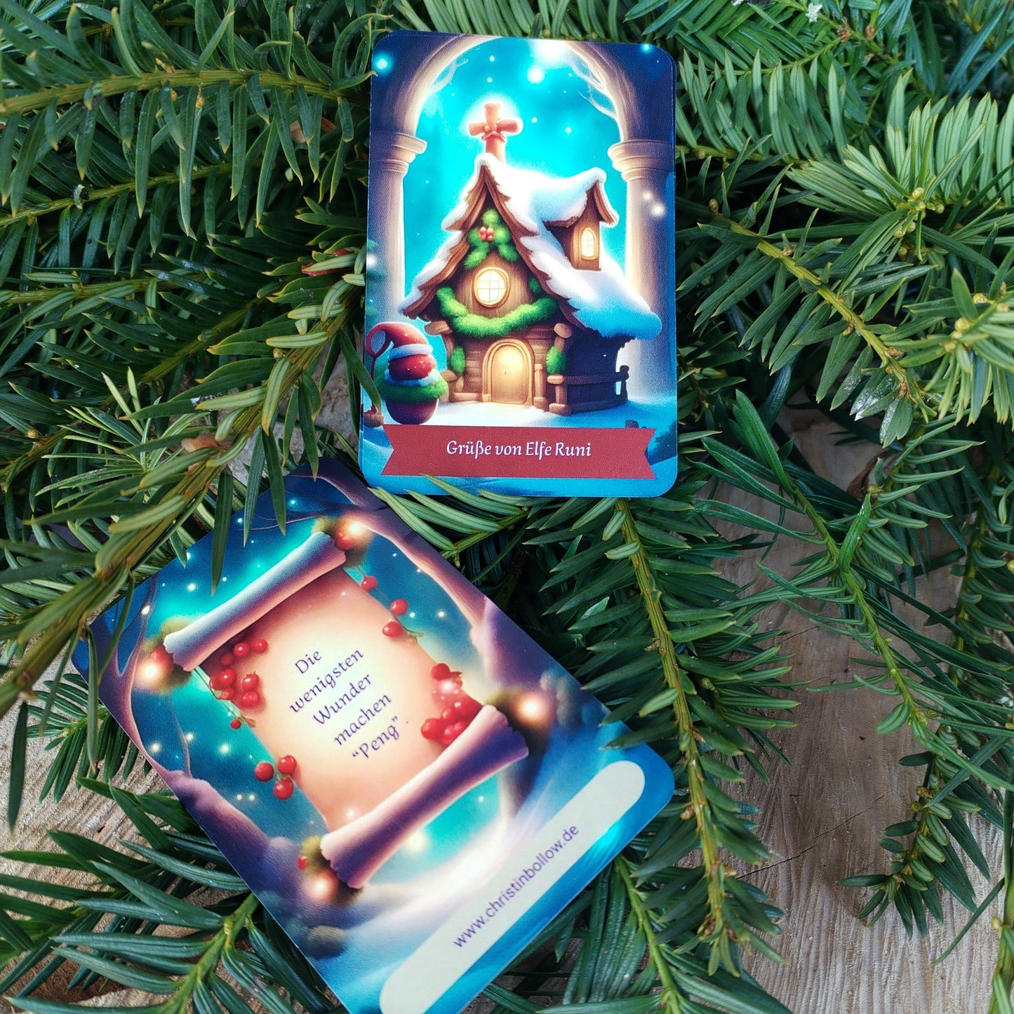 Kartendeck 'Post von Runi'. Das Dezemberdeck liegt mit einer Vorder- und Rückseite der Bonus-Karte auf einer Holzscheibe und frischen Nadelbaumzweigen.