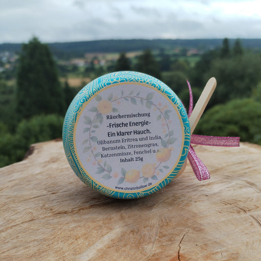 Räuchermischung 'Frische Energie', abgefüllt in einer bunten Metalldose, die auf einer Holzscheibe steht. Im Hintergrund Natur. Produktbild 2, Handgemachte Räuchermischungen von Christin Bollow