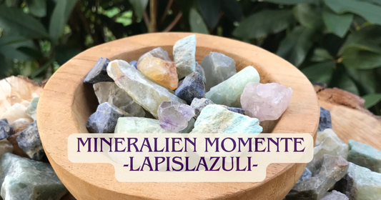 Bannerbild: Mineralien Momente -Lapislazuli-, eine Holzschale gefüllt mit verschiedenen Steinen, im Hintergrund Natur.