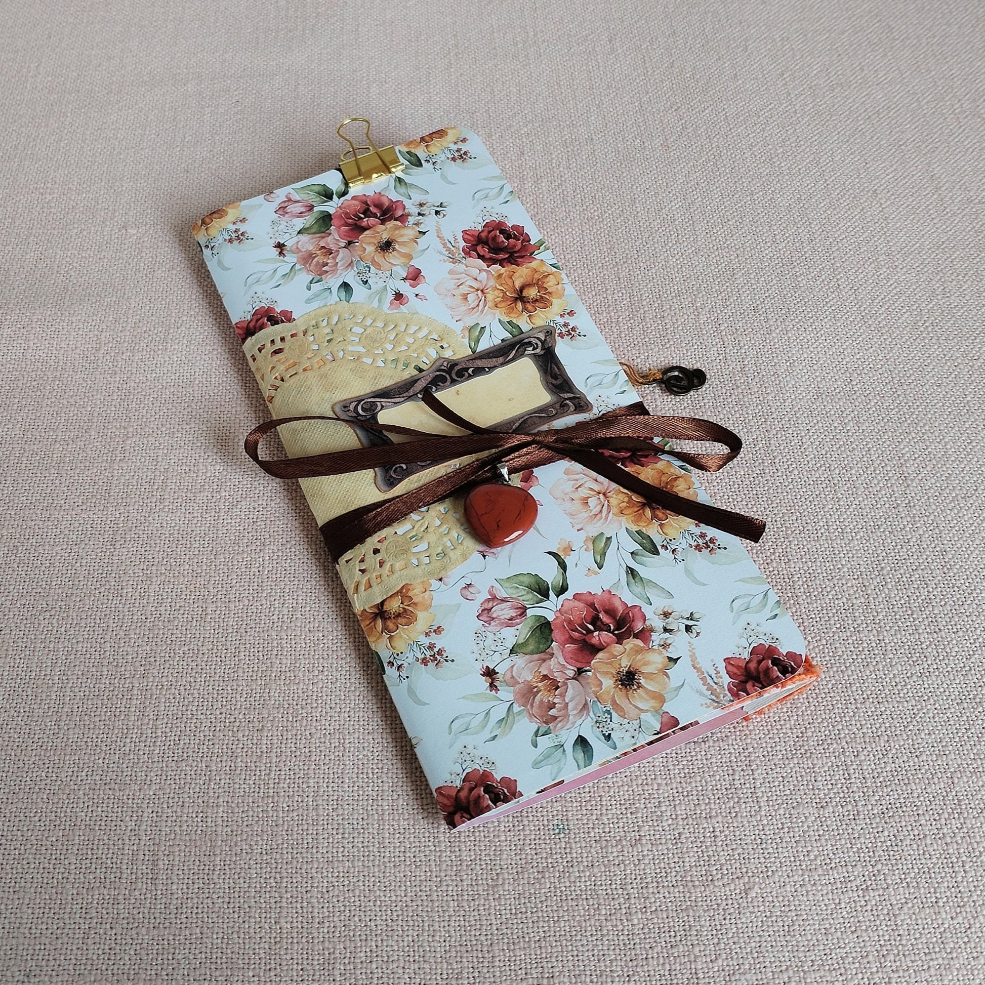 Long-Slim-Journal Motiv Rosen in herbstlichen Farben Vorderseite mit einem  kleinen Kettenanhänger aus rotem Jaspis an einem braunen Satinband.